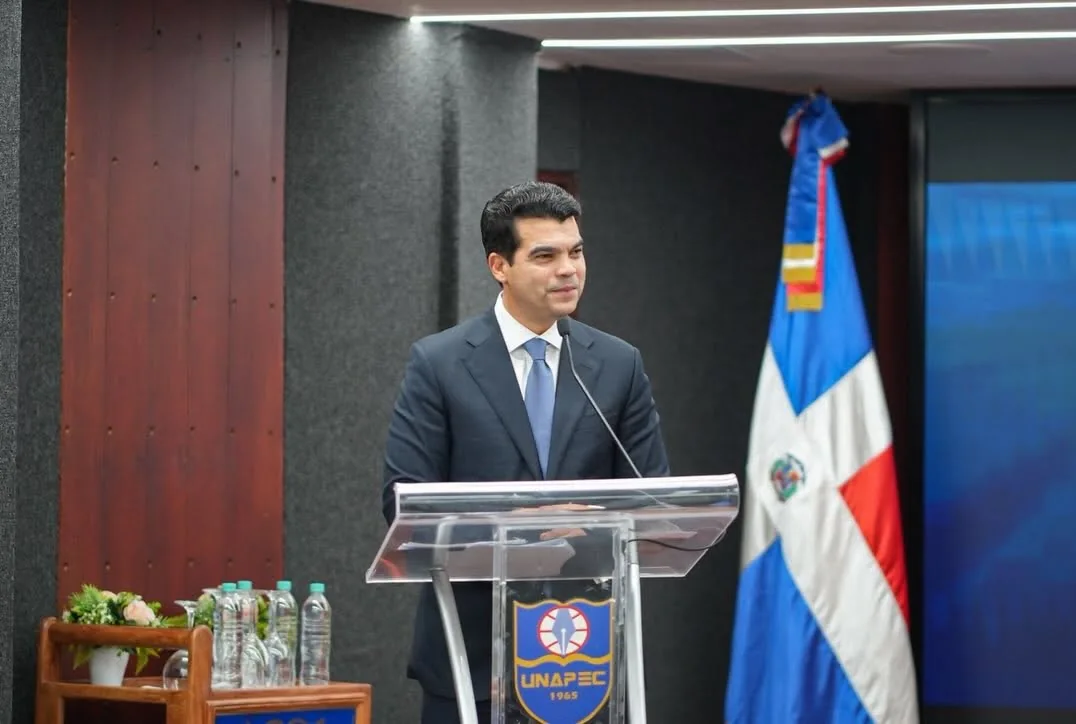 Wellington Arnaud interviene desde un podio con la bandera dominicana.